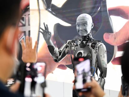 Attendees take pictures and interact with the Engineered Arts Ameca humanoid robot with artificial intelligence as it is demonstrated during the Consumer Electronics Show (CES) on January 5, 2022 in Las Vegas, Nevada. (Photo by Patrick T. FALLON / AFP) (Photo by PATRICK T. FALLON/AFP via Getty Images)