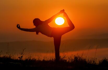 Una mujer hace yoga al amanecer.