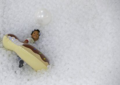 Un niño juega con un flotador en una piscina repleta de bolas de plástico conocida como 'La playa', en un centro comercial de Bangkok (Tailandia). La instalación interactiva, creada por Snarkitecture, pretende simular una playa en la que la arena y el mar son reemplazados por unas 250.000 bolas de plástico reciclado antimicrobianas.