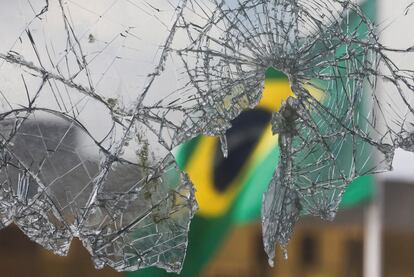 Una bandera brasileña se ve a través de cristales rotos tras los disturbios registrados el domingo en Brasilia.