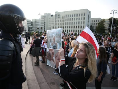 Uma mulher segura uma foto em frente a um policial de uma pessoa torturada durante protesto em Minsk neste sábado.