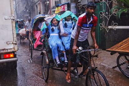 Dos niñas con ropa escolar se protegen de la lluvia mientras viajan en un 'rickshaw' en Dhaka, Bangladesh, este miércoles.