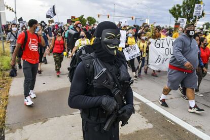 Un manifestante disfrazado sujeta un arma durante una protesta que ha cortado el tráfico en la autovía I-225, en Aurora (Colorado).