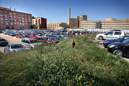 El gran solar del barrio de Tendetes, con los coches aparcados, las hierbas y el hospital La Fe  al fondo.