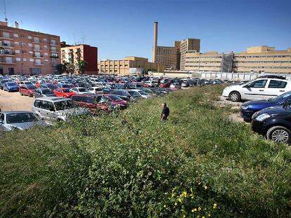 El gran solar del barrio de Tendetes, con los coches aparcados, las hierbas y el hospital La Fe al fondo.