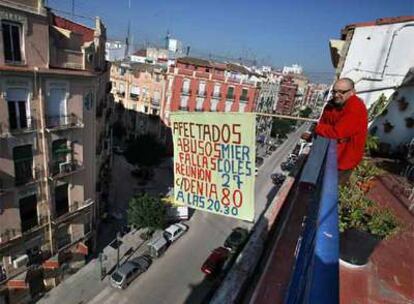 Uno de los vecinos afectados, ayer, junto a la pancarta que convoca a una reunión sobre los abusos falleros.