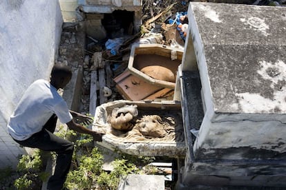 Loubert Gouin mueve un ataúd roto que contiene los restos de un cadáver exhumado, en una vieja tumba en el cementerio nacional de Puerto Príncipe, en Haití. Los trabajadores del cementerio dicen que generalmente tiran los huesos en una bóveda o que temporalmente los dejan apartados en un rincón para dejar espacio al siguiente cliente. Pocas familias acuden a recoger los restos.