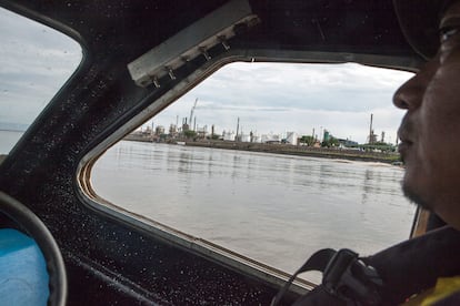 Una embarcación de transporte navega por el Río Magdalena con la refinería de Barrancabermeja de fondo.