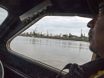 Una embarcación de transporte navega por el Río Magdalena con la refinería de Barrancabermeja de fondo.