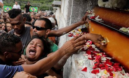 Luciana Nogueira, esposa de Evaldo Rosa dos Santos, no enterro do marido. Amigos do músico protestaram com bandeiras do Brasil manchadas de vermelho