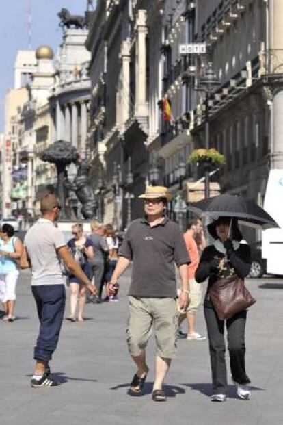 Varios turistas japoneses se protegen del sol con un paraguas durante durante una visita a la Puerta del Sol, en el centro de Madrid. EFE/Archivo