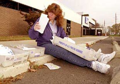 Una empleada de correos revisa algunas cartas sentada fuera de la oficina de Hamilton Township (Nueva Jersey).
