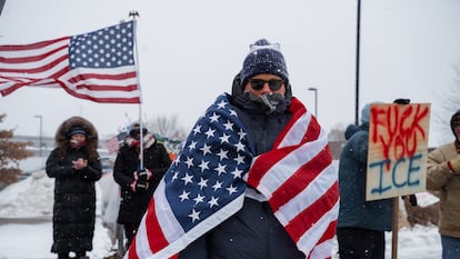 A person wraps themselves in a United States flag during a protest against ICE in Minneapolis