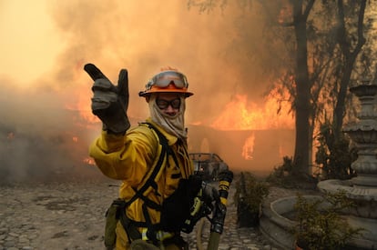 Tres hombres han sido detenidos en relación con un incendio iniciado hoy unos 50 kilómetros al norte de la ciudad estadounidense de Los Ángeles, que ha obligado a evacuar a decenas de personas y aún no ha sido controlado. En la imagenm, un bombero pide más agua durante en el incendio de una casa en Glendora, California.