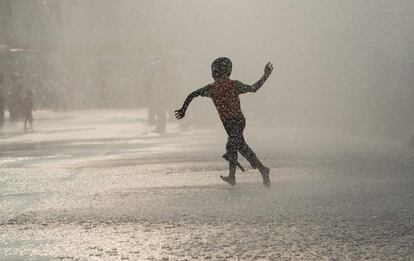 Un niño se divierte bajo unos aspersores de agua instalados frente al ayuntamiento de Yangon (Myanmar).