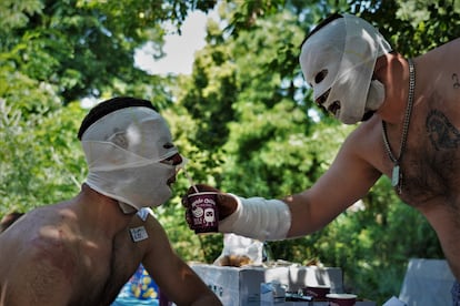 UIurii (right), 30, helps a colleague drink after being treated for burns at a makeshift hospital a few kilometers from the front line in Ukraine, after his armored vehicle was hit by a Russian missile, July 18.
