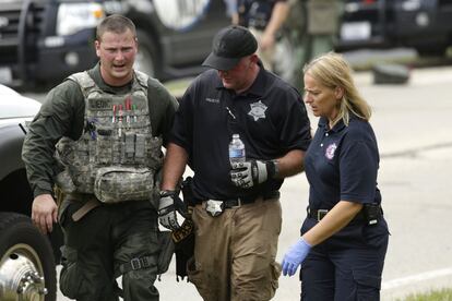 A police officer is lead to an ambulance in the scorching heat during a manhunt after an officer was shot and killed while pursuing a group of suspicious men, Tuesday, Sept. 1, 2015. Authorities in Fox Lake, 55 miles north of Chicago,  have notified a number of other law enforcement agencies to ask for assistance, including the FBI, which is sending agents to help in the investigation. (Stacey Wescott/Chicago Tribune via AP) MANDATORY CREDIT CHICAGO TRIBUNE; CHICAGO SUN-TIMES OUT; DAILY HERALD OUT; NORTHWEST HERALD OUT; THE HERALD-NEWS OUT; DAILY CHRONICLE OUT; THE TIMES OF NORTHWEST INDIANA OUT; TV OUT; MAGS OUT; NO SALES   