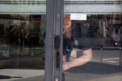 Una empleada de Starbucks, en la calle de Alcalá de Madrid, echa el cierre al establecimiento después de que el Gobierno haya anunciado que decretará el estado de alarma. Aunque las medidas que obligan al cierre de establecimientos entrarán en vigor mañana, muchos comercios se han anticipado y han cerrado ya hoy.