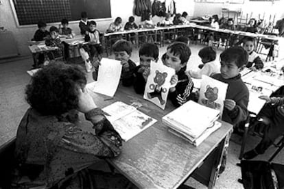 Unos niños enseñan sus dibujos a una profesora durante una clase.