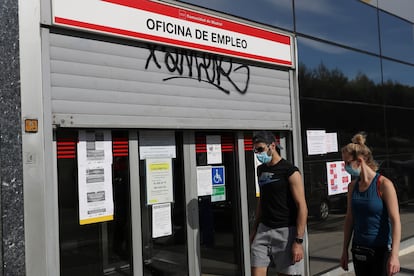 Dos jóvenes pasan ante una oficina de empleo en Madrid, en mayo pasado.