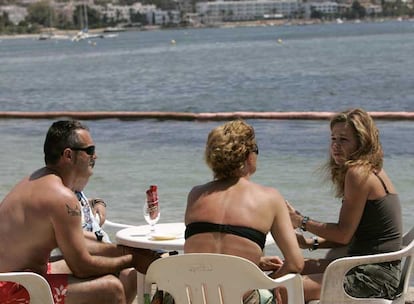 Tres turistas, en una terraza de la playa de Talamanca (Ibiza).