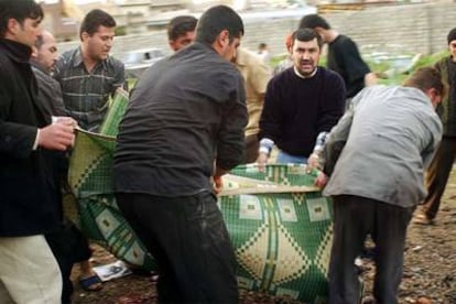 Un grupo de personas traslada el cadáver de una de las víctimas del atentado en Mosul.