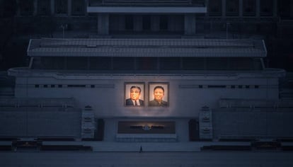 Homem passeia sob os dois grandes retratos de Kim Il-sung (esq.) e Kim Jong-il (dir.) em Pyongyang.