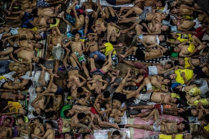 Reclusos durmiendo acinados en una cancha de baloncesto de la prisión de Quezon, Manila.