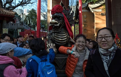 Un grupo de personas tocan la estatua del dragón para que tener buena suerte durante las celebraciones del Año Nuevo Chino en un templo en Hong Kong.