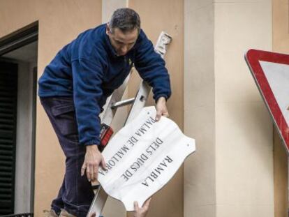 Un operario retira la placa de la calle de Los duques de Palma de Mallorca, el pasado febrero. 
