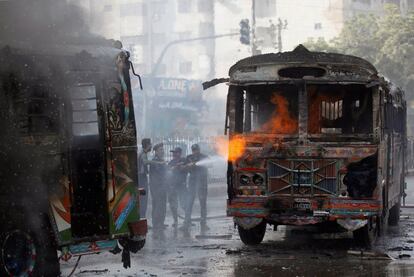 Bomberos tratan de apagar unos autobuses en fuego que, segn los medios, fueron incendiados por la gente despus de que una chica fuera asesinada por exceso de velocidad en una carretera de Karachi (Pakistn).