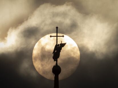 La veleta emblemática de San Petersburgo (Rusia) en forma de ángel, fijada en lo alto de una aguja de la Catedral de los santos Pedro y Pablo, se siluetea contra el sol en las nubes.