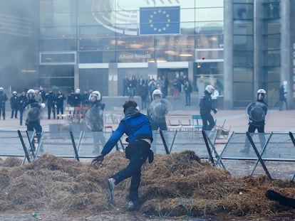 A demonstrator throws an object towards police officers in riot gear outside the European Parliament as farmers from European countries protest over price pressures, taxes and green regulation, in Brussels, Belgium February 1, 2024.