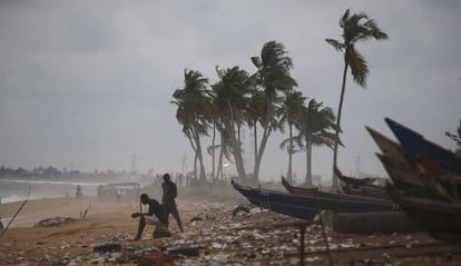 Varios pescadores sentados junto a unas canoas en una playa en Abidjan, Costa de Marfil.