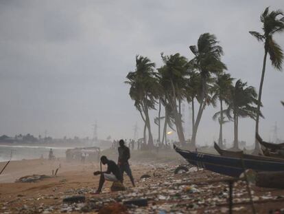 Varios pescadores sentados junto a unas canoas en una playa en Abidjan, Costa de Marfil.