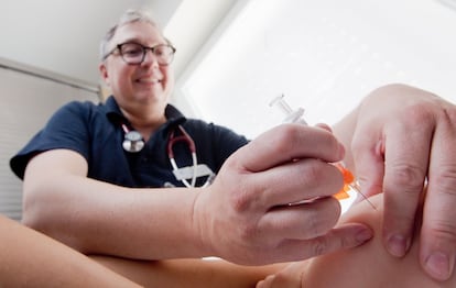 Un niño es vacunado frente al sarampión por personal sanitario.