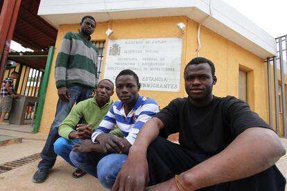 Un grupo de inmigrantes subsaharianos sentados frente a la puerta del  CETI de Melilla.