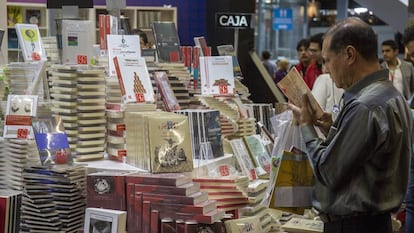 Un hombre ojea un libro en la FIL de Guadalajara.
