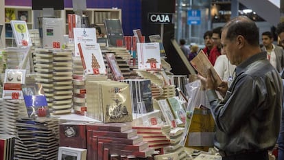 Un hombre ojea un libro en la FIL de Guadalajara.