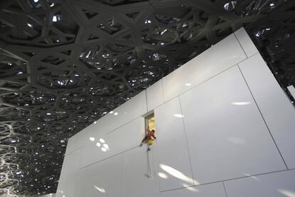 Um trabalhador limpa uma janela sob a cúpula do museu Louvre de Abu Dhabi. “Quero pensar no conjunto como em uma medina árabe, com suas ruas estreitas que separam as casas”, disse o arquiteto Jean Nouvel, que defende como estratégia a junção com as tradições construtivas do local em frente aos edifícios que caem como “paraquedistas”.