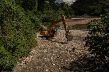 Una máquina excavadora trabaja en uno de interceptores de basura colocados en el río Las Vacas.