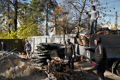 Empleados pesan la chatarra retirada del edificio tras los daños causados por los ataques rusos para comprársela a los vecinos.