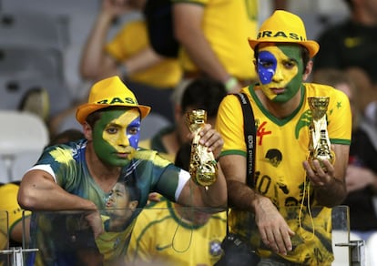 Dois torcedores de caras pintadas com a bandeira do Braisl levantam a taça de cabeça para baixo após a semifinal que a seleção brasileira perdeu para a Alemanha.