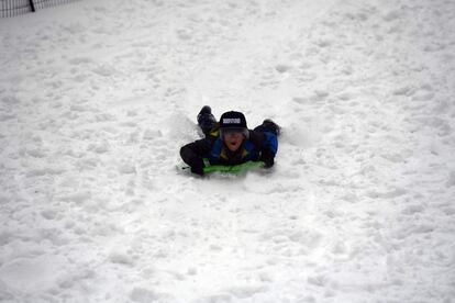 Un niño se desliza con un trineo sobre la nieve en Central Park, Nueva York.