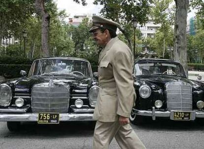 Uno de los figurantes de la película de Soderbergh, vestido de militar, pasa por delante de los coches oficiales de época, ayer, en Madrid.
