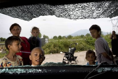 Varios niños se asoman por la ventanilla de un coche destrozado en un campamento de gitanos rumanos en Casoria, cerca de Nápoles.