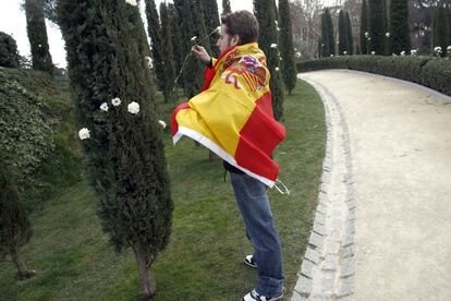 Un joven, envuelto en una bandera española, coloca una flor en uno de los cedros del Bosque del Recuerdo, en el parque del Retiro, conmemorando el sexto aniversario del atentado terrorista del 11-M. Marzo de 2010.