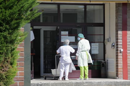 Dos trabajadores en la entrada de una residencia donde ha habido un brote, en Lugo.