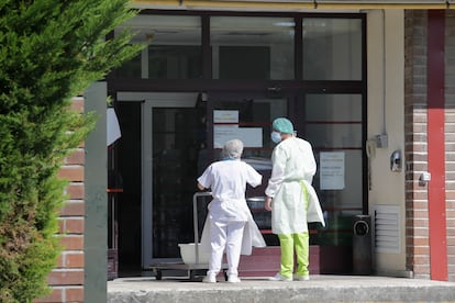 Dos trabajadores en la entrada de una residencia donde ha habido un brote, en Lugo.