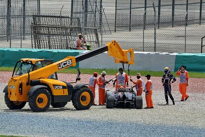 El piloto de Red Bull observa cómo la grúa se lleva su bólido de la gravilla del circuito de Malaisia durante los entrenamientos libres.